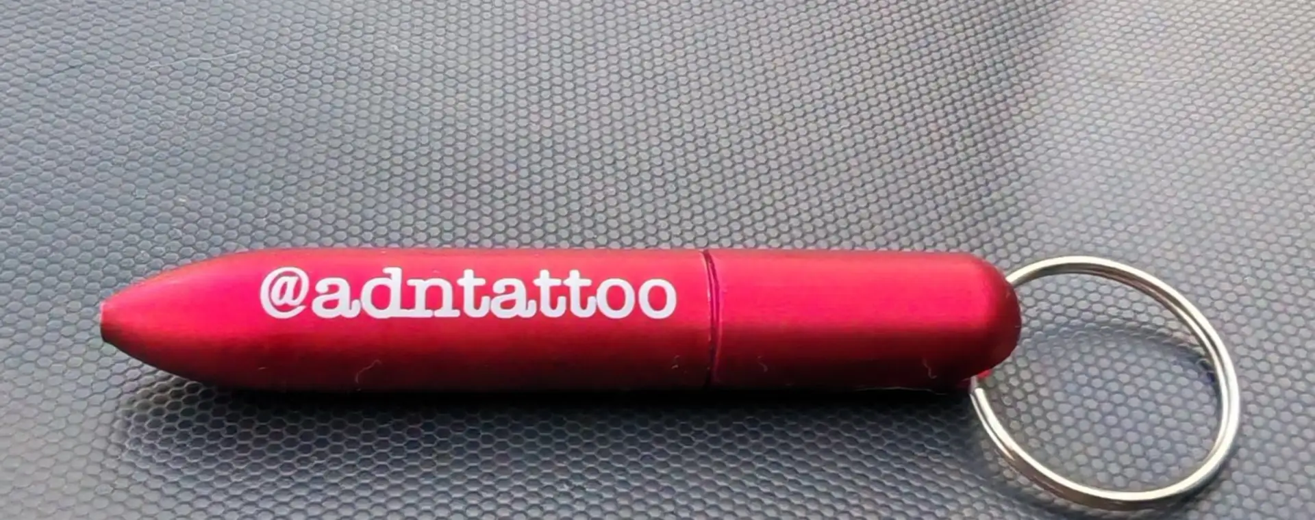Llavero metálico fucsia con el nombre de una marca grabado