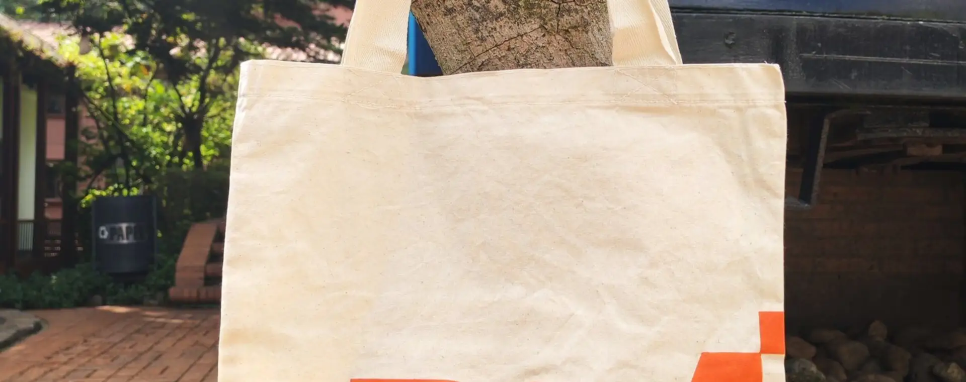 Bolsa de tela cruda con diseño estampado colgada de un árbol