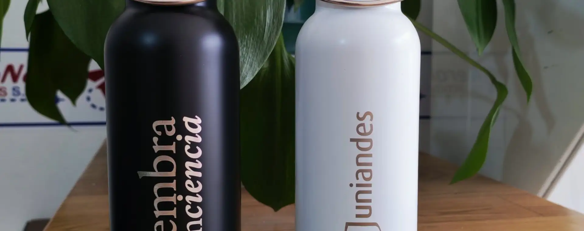 Botellas metálicas negra y blanca con tapa de bambú y mensaje ambiental