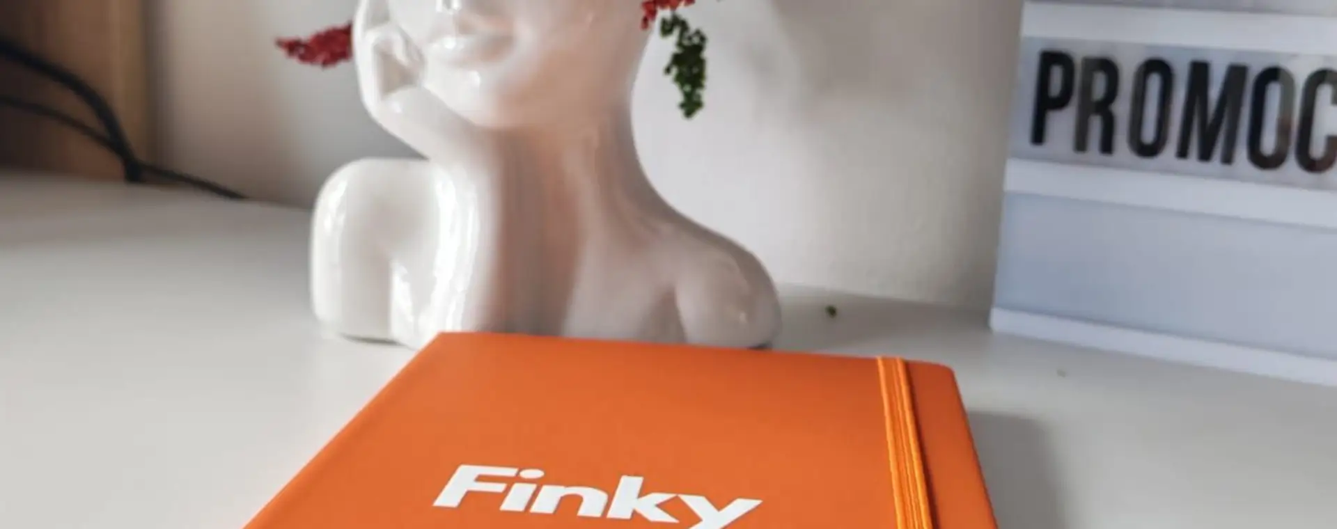 Libreta naranja personalizada con logo blanco junto al aviso de MG Promocionales