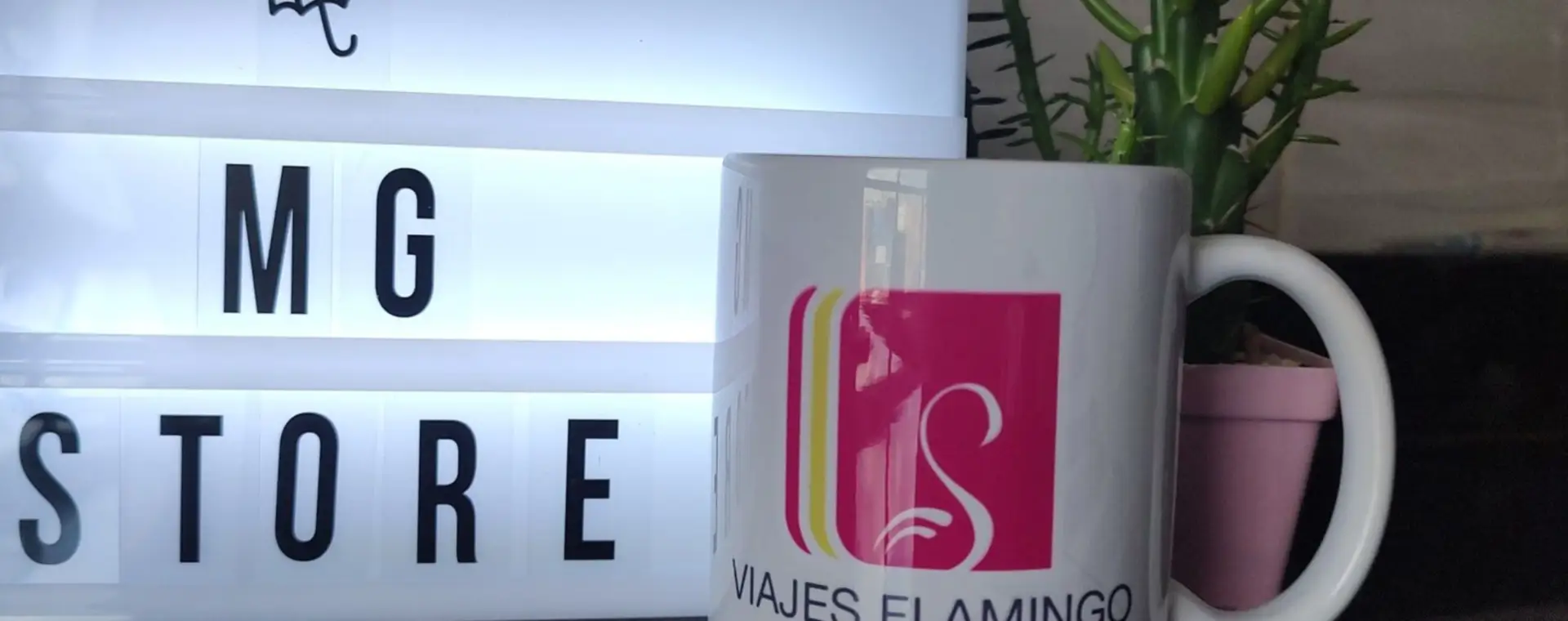 Mug personalizado con logo de agencia de viajes junto al letrero luminoso de MG Store